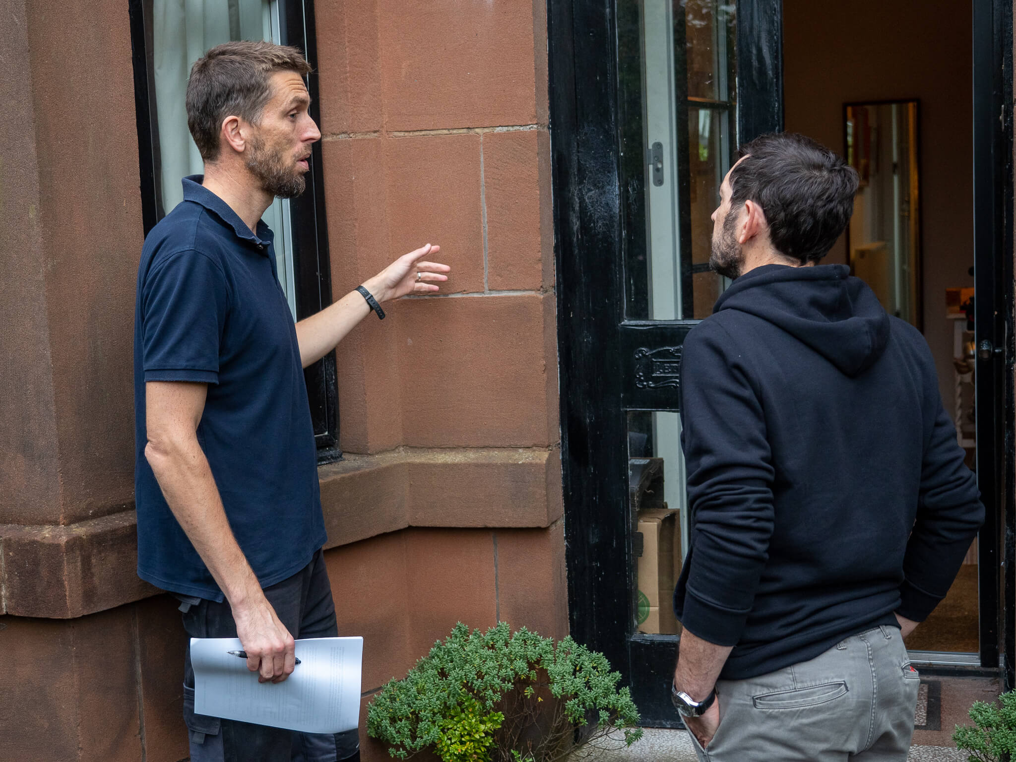 Loco Home employee pointing at mortar on redstone building in Glasgow with customer who owns a tenement