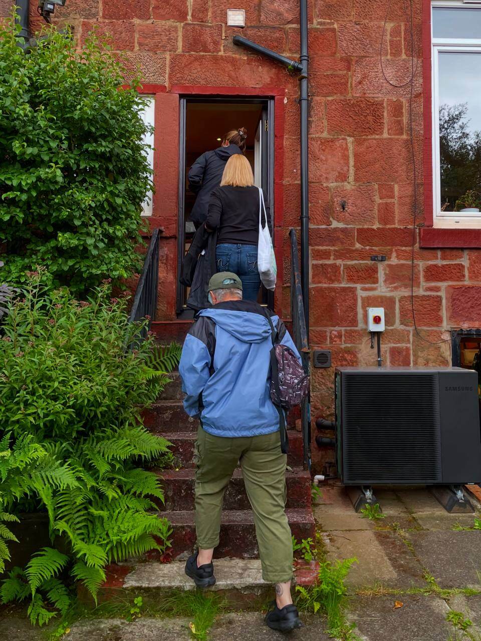 red background circles loco home services in glasgow first circle top right, CHRIS sitting down with someone showing them their retrofit plan, next someone reaching out for a heat pump and hearing the sound. Last circle loco home surveyor talking to tradesperson