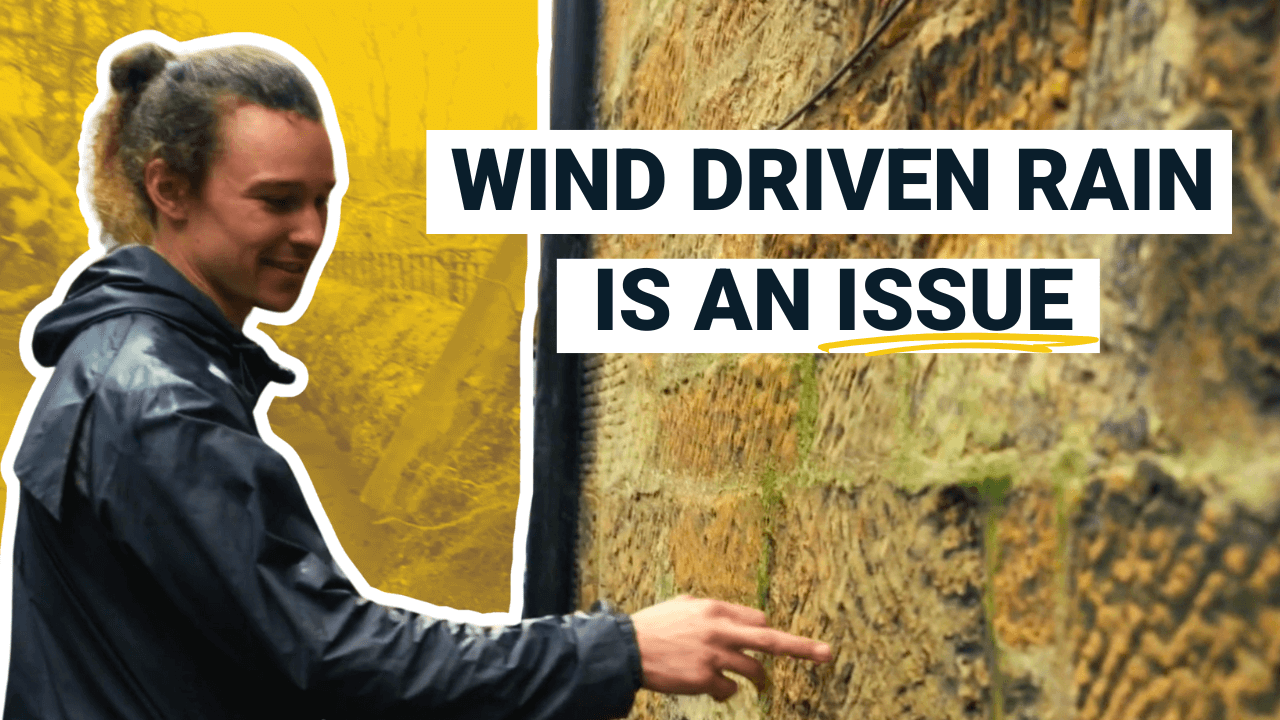 man in his twenties points at sandstone building with erosion in glasgow due to driving rain. Quotes "Wind driven rain is an issue"